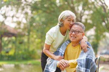 Elderly couple husband and wife happy asian people giving love and care Wheelchair in the park relaxing in spring, relaxing and walking outside at the park.