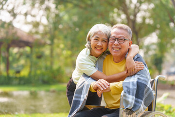 Naklejka na ściany i meble Elderly couple husband and wife happy asian people giving love and care Wheelchair in the park relaxing in spring, relaxing and walking outside at the park.