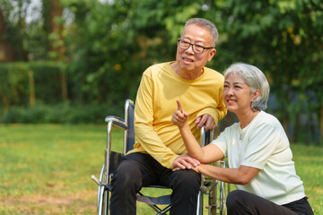Elderly couple husband and wife happy asian people giving love and care Wheelchair in the park relaxing in spring, relaxing and walking outside at the park.