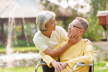 Elderly couple husband and wife happy asian people giving love and care Wheelchair in the park relaxing in spring, relaxing and walking outside at the park.