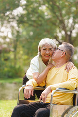 Elderly couple husband and wife happy asian people giving love and care Wheelchair in the park relaxing in spring, relaxing and walking outside at the park.