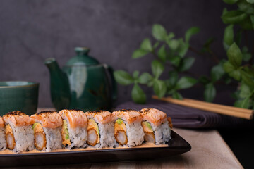 tempura sushi roll topped with seared salmon and serve with hot tea. Japanese traditional dishes and healthy food.