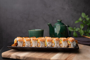 tempura sushi roll topped with seared salmon and serve with hot tea. Japanese traditional dishes and healthy food.
