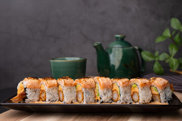 tempura sushi roll topped with seared salmon and serve with hot tea. Japanese traditional dishes and healthy food.