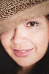 Imagen vertical de rostro de mujer adulta sonriendo con sombrero, un ojo tapado y el otro mirando al frente