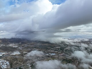 Aerial shot of a drone in a city with a big cloud in front