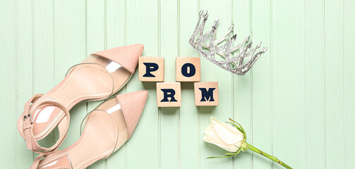 Cubes with word PROM, tiara, rose and female shoes on green wooden background