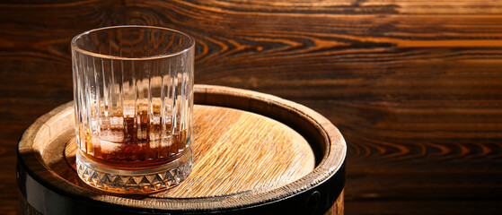 Glass of whiskey on wooden barrel