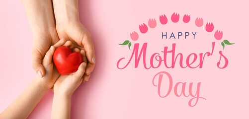 Hands of woman and child with red heart on pink background. Greeting card for Mother's Day