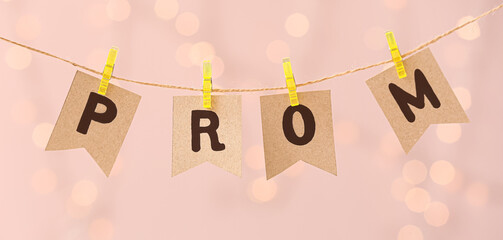 Rope, clothespins and paper flags with word PROM against blurred lights © Pixel-Shot