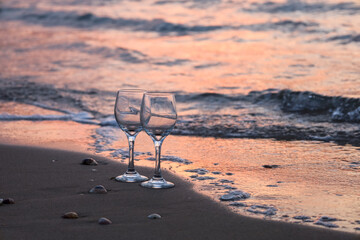 Empty wine glasses on seashore at sunset