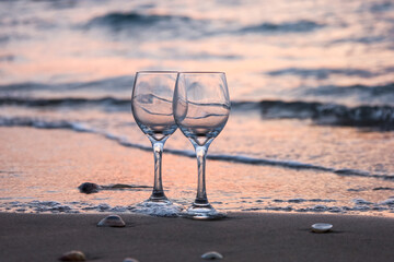 Empty wine glasses on seashore at sunset