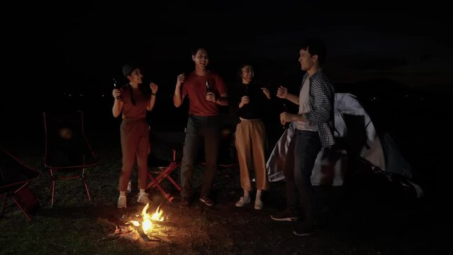 Asian friends camping holiday, Singing, Dancing around a bonfire, drinking beer in the dusk, Lifestyle Relaxation, Vacations Camping trip, Travel