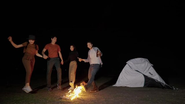 Asian friends camping holiday, Singing, Dancing around a bonfire, drinking beer in the dusk, Lifestyle Relaxation, Vacations Camping trip, Travel