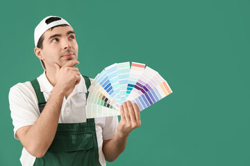 Thoughtful male painter with color palettes on green background