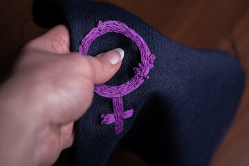 mano sosteniendo paño con símbolo feminista bordado, como instrumento de protesta
