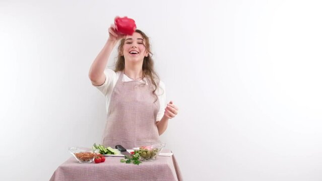 slow motion full HD 240fps young girl woman tossing red bell pepper laughing sincerely on white background space and place for text cooking show cooking appetite delicious vegetable salad vegetarian