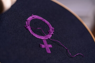 detalle de símbolo feminista bordado recién terminado con hilo suelto, sobre bastidor redondo de madera - obrazy, fototapety, plakaty