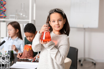 Little girl with safety goggles and conical flask in science classroom