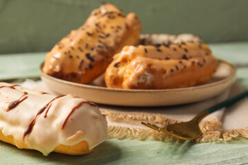 Delicious eclair on green wooden table, closeup