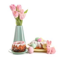 Tasty Easter cakes, tulip flowers, eggs and toy bunny on white background