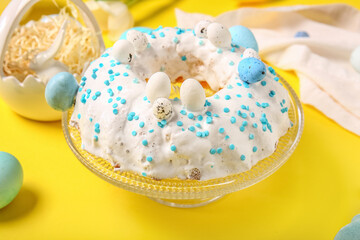 Dessert stand with tasty Easter cake on yellow background