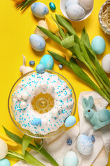 Composition with tasty Easter cake, painted eggs and tulip flowers on yellow background