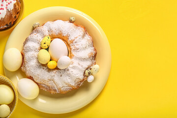 Plate with sweet Easter cake and painted eggs on yellow background
