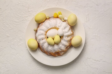 Plate with sweet Easter cake and eggs on light background
