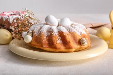 Plate with tasty Easter cake, eggs and beautiful gypsophila flowers on grey table
