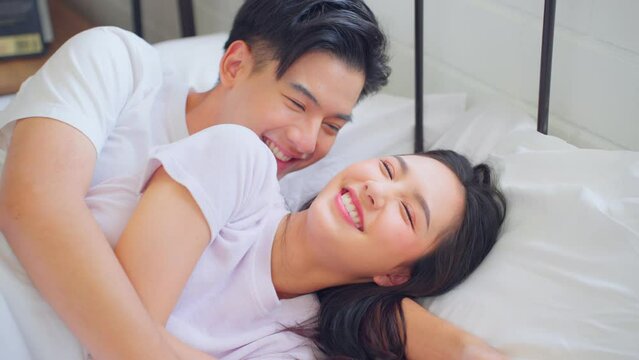 Asian attractive young couple lying down on bed to sleep in bedroom.