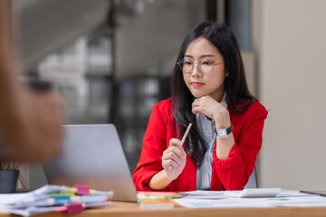 Asian businesswoman analyzing reports while working in workplace office.