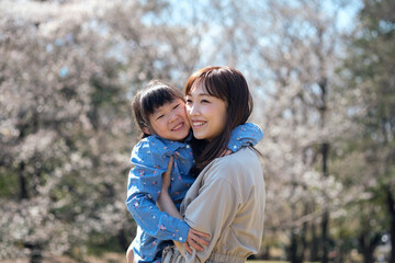桜の咲く公園で遊ぶ母と娘