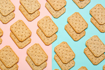 Many delicious crackers on pink and turquoise background