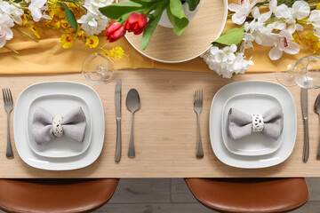 Setting for International Women's Day celebration with flowers, cutlery and napkins on table