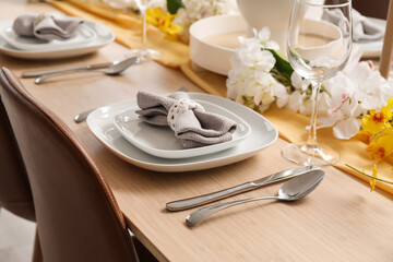 Setting for International Women's Day celebration with flowers, cutlery and napkin on table, closeup