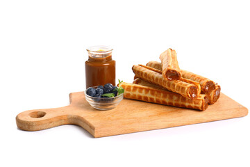 Board with delicious wafer rolls, boiled condensed milk and blueberries isolated on white background