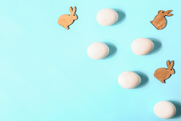 Natural Easter eggs and wooden bunny figures on color background