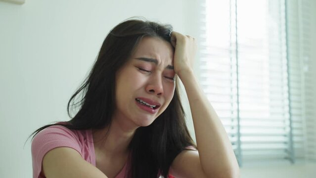 Asian beautiful woman feel angry while sitting alone on bed in bedroom
