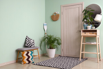 Interior of stylish hall with bench, houseplants and table