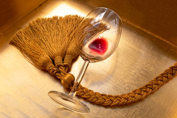 A half empty glass of red wine on a gold background