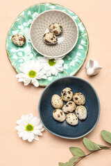 Composition with Easter quail eggs, chamomile flowers and eucalyptus branch on beige background