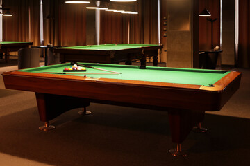 Billiard tables with balls and cues in club