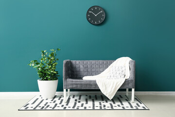 Stylish grey sofa and houseplant near green wall