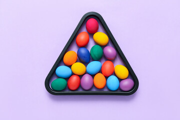 Colorful Easter eggs in triangle rack on lilac background