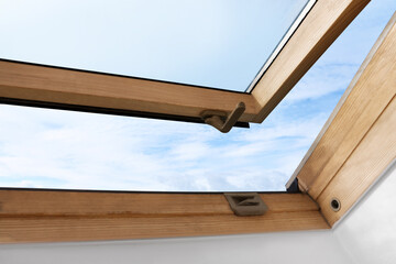 Beautiful view of cloudscape from open skylight roof window on slanted ceiling. Attic room
