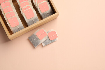Many tea bags in wooden box on color background, flat lay. Space for text