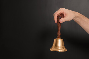Teacher with school bell near black chalkboard, closeup. Space for text
