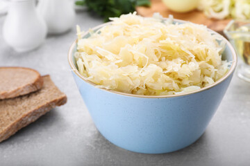 Bowl of tasty sauerkraut on grey table, closeup