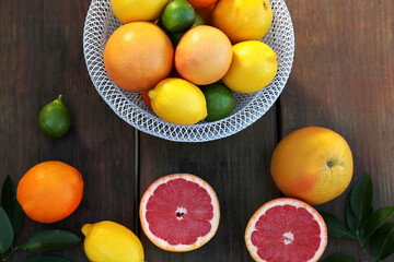 Different citrus fruits and leaves on wooden table, flat lay